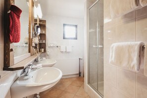 Un baño con dos lavamanos, un espejo, toallero, ducha y ventana.