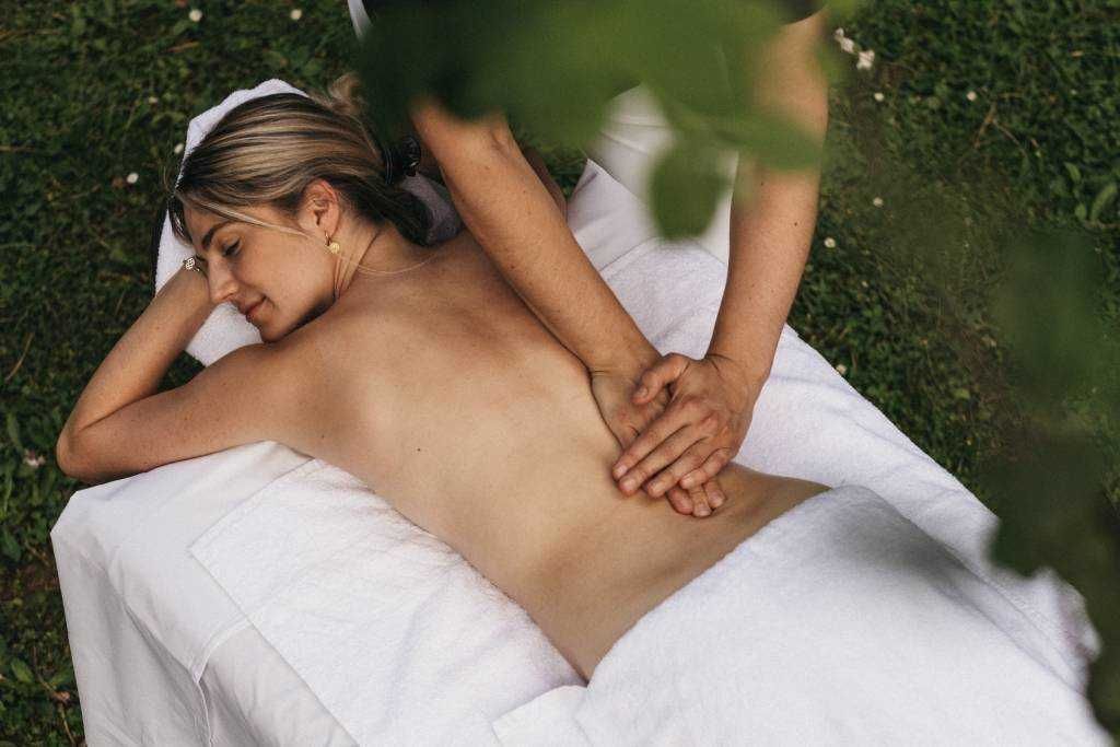 A person receiving a massage on a white towel outdoors.