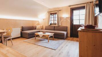 A cozy living room with a sofa, a coffee table, and a dining area with a table and chairs.