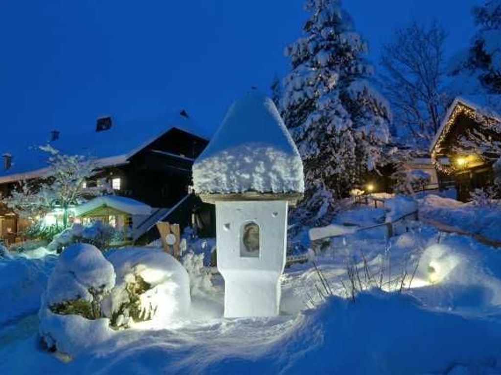 Un bâtiment enneigé, doté d’un toit conique et d’une petite fenêtre, entouré de neige et d’arbres.