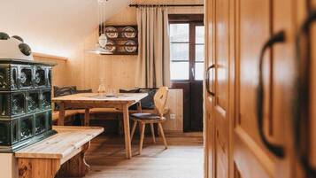 Ein Holzinterieur mit einem Esstisch, Stühlen, einer Bank und einem grünen Schrank.