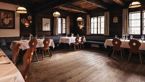 A restaurant with wooden floors, tables set with white tablecloths, and wooden chairs.