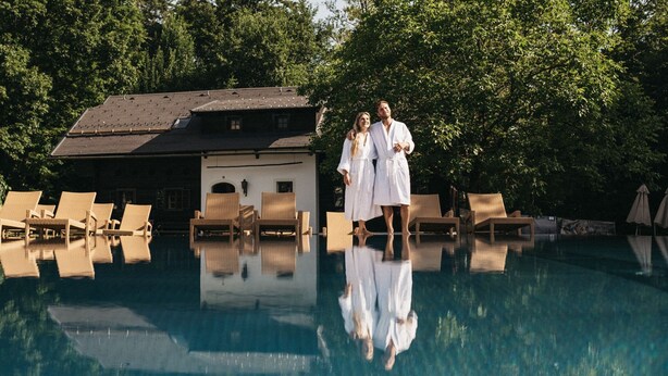 A swimming pool with lounge chairs and a building in the background.