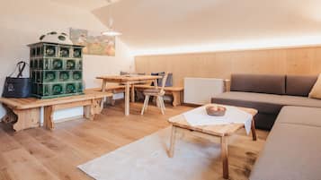 A cozy living room with a wooden bench, a dining table, a sofa, and a radiator.