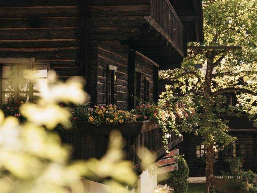Un bâtiment en bois doté d’un balcon, entouré de verdure.