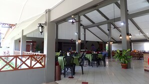 An indoor dining area with tables and chairs, a ceiling with beams, and hanging lights. - Lemonia Holiday Resort (Langkawi)