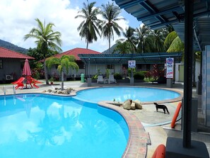 A swimming pool with a red roofed structure, palm trees, and a sign indicating no swimming. - Lemonia Holiday Resort (Langkawi)