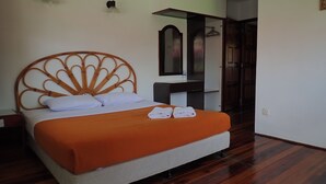A neatly made bed with an orange bedspread and white pillows, a wooden headboard, a small bedside table with a mirror, and a wardrobe with a mirror. - Lemonia Holiday Resort (Langkawi)