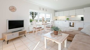Un salon moderne comprenant un téléviseur, un coin repas et une cuisine.