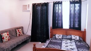 Um quarto com uma cama, um sofá e duas cortinas.