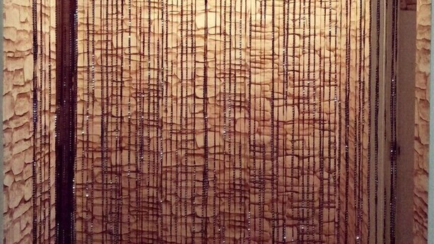 Um quarto com parede texturizada, um banco e uma pequena janela.