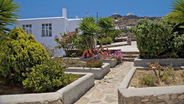 A white building with a stone pathway leading to a hilltop view. - Evagelia's Place (Mykonos)