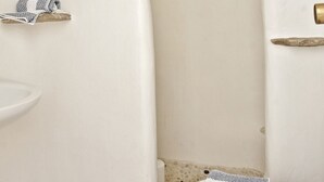 A bathroom with a white toilet, a small sink, and a towel rack. - Evagelia's Place (Mykonos)