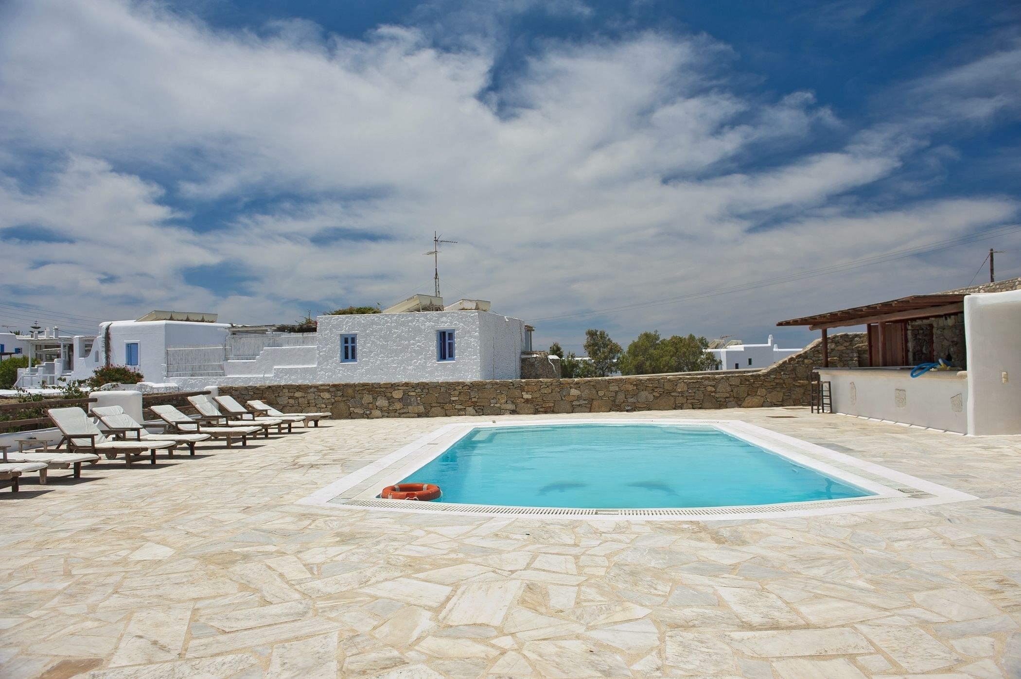 A swimming pool with lounge chairs and a stone wall.