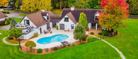 A residential property with a swimming pool, a covered patio, and a well-maintained lawn.