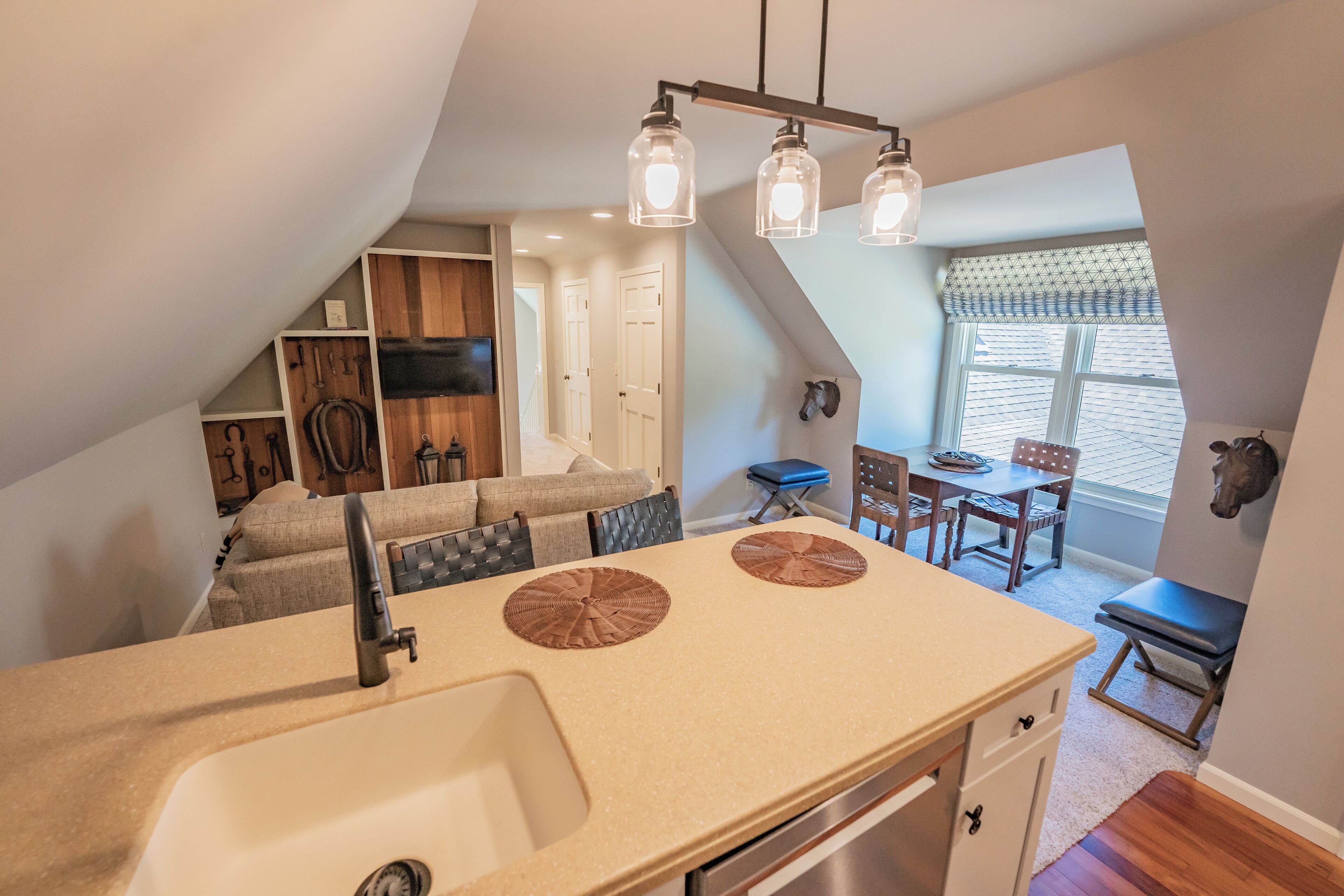 A kitchen with a sink, two circular mats, and a dining area with a table and chairs.