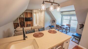 A kitchen with a sink, two circular mats, and a dining area with a table and chairs.