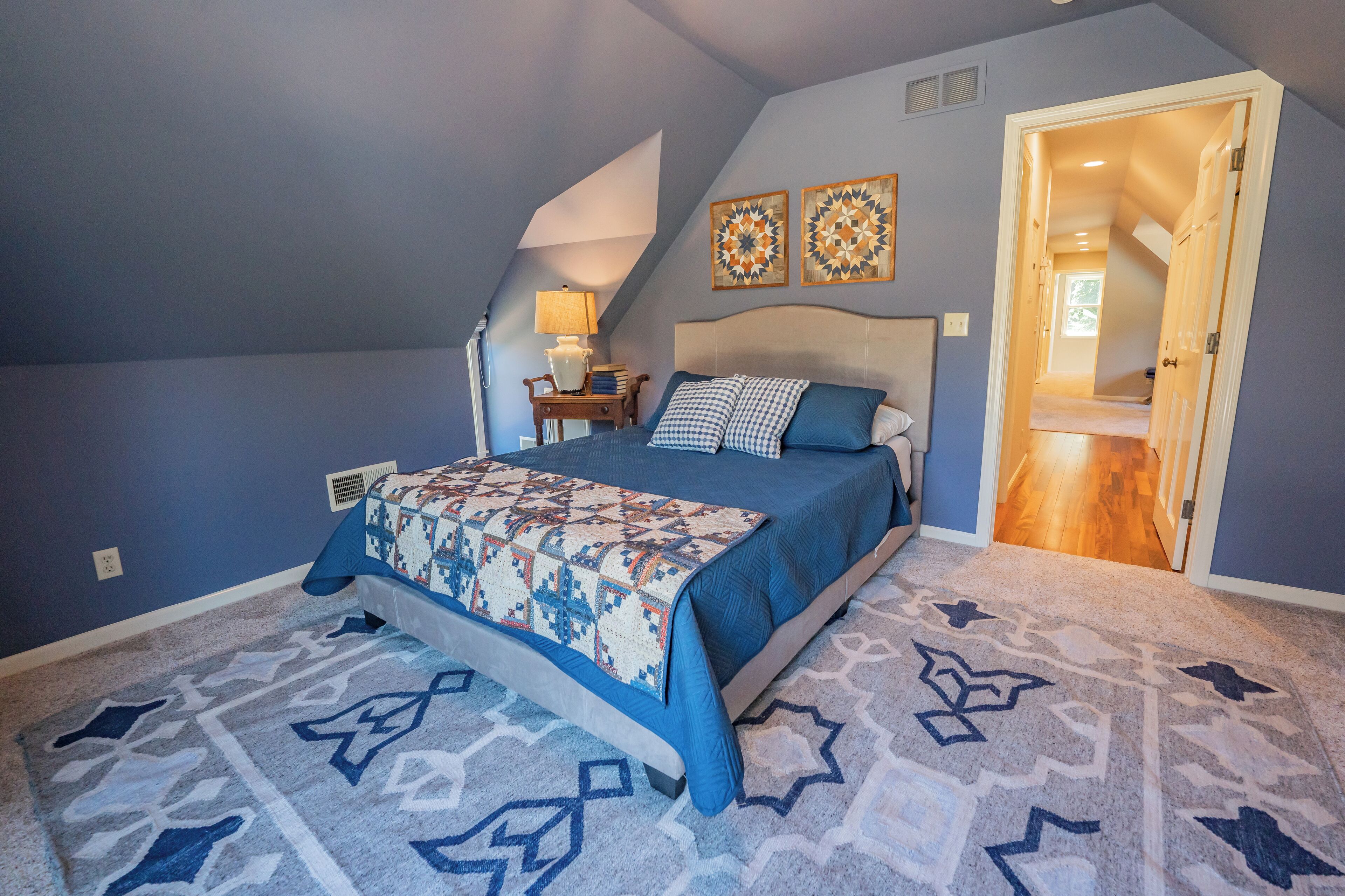 A bedroom with a bed, a nightstand, a lamp, and two wall art pieces.