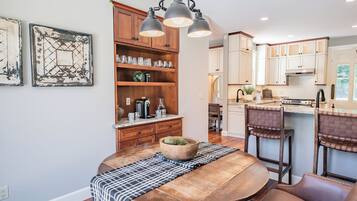 A modern kitchen with wooden cabinets, a dining table with a placemat, and pendant lighting.
