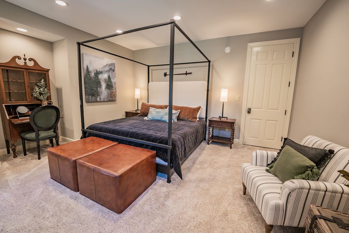 Een slaapkamer met een hemelbed, een bureau met stoel, een bank en een kast.