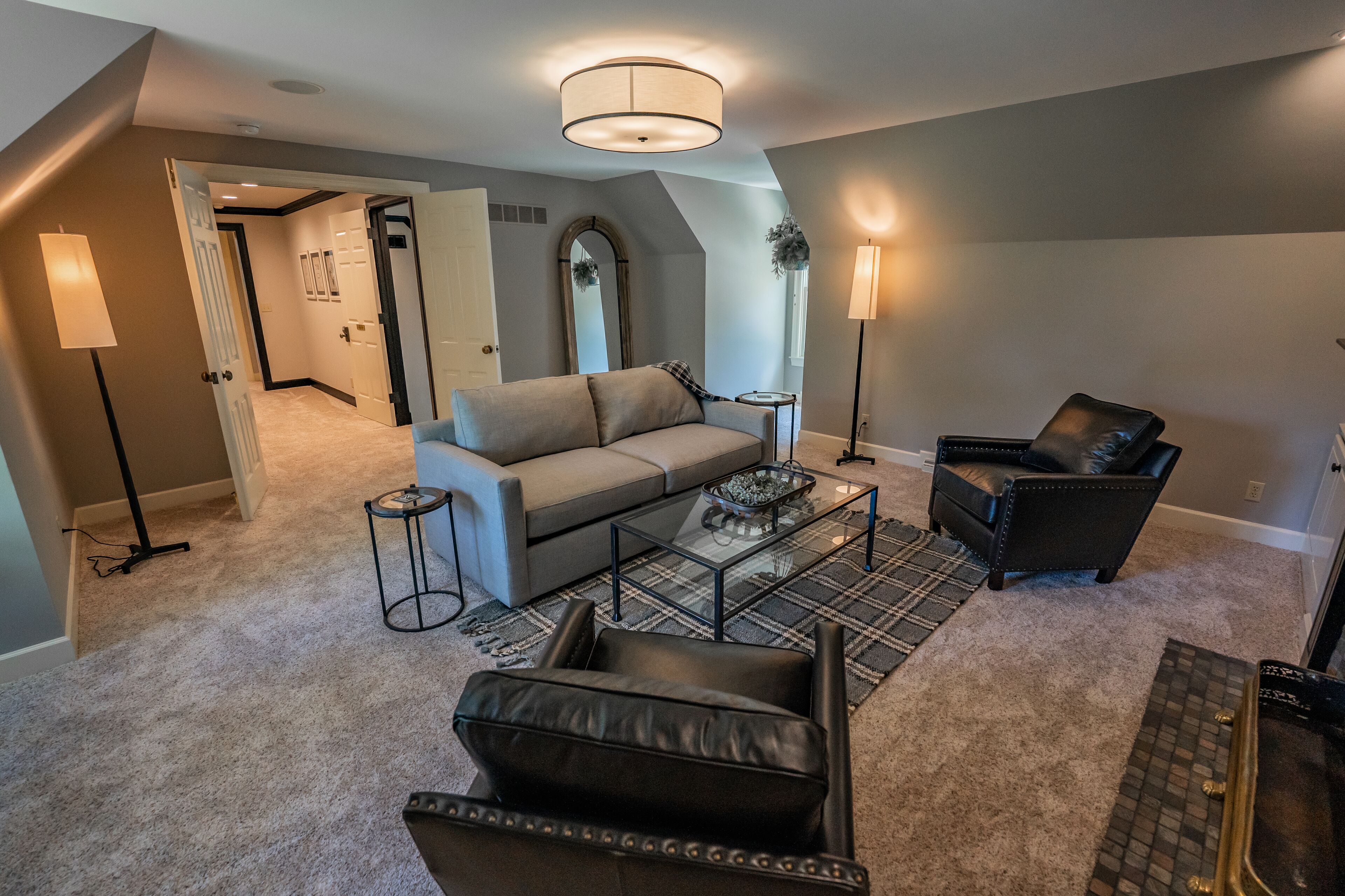 A living room with a sofa, a leather chair, a coffee table, and a lamp.