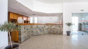 A reception area with a stone counter, wooden cabinets, and potted plants. - Notos Hotel (Rhodes)