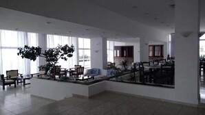 A spacious lobby with a seating area, large windows, and a central plant. - Notos Hotel (Rhodes)
