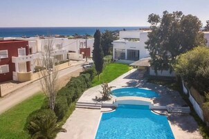 Una piscina al aire libre, sombrillas, sillones reclinables de piscina