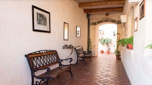 A corridor with benches, framed pictures on the walls, and potted plants. - Country View (Ghasri)