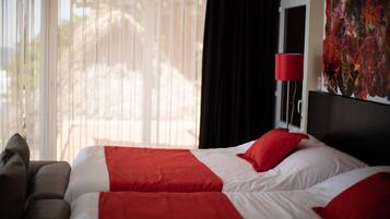 A hotel room with a bed, a red lamp, and a large abstract painting on the wall.