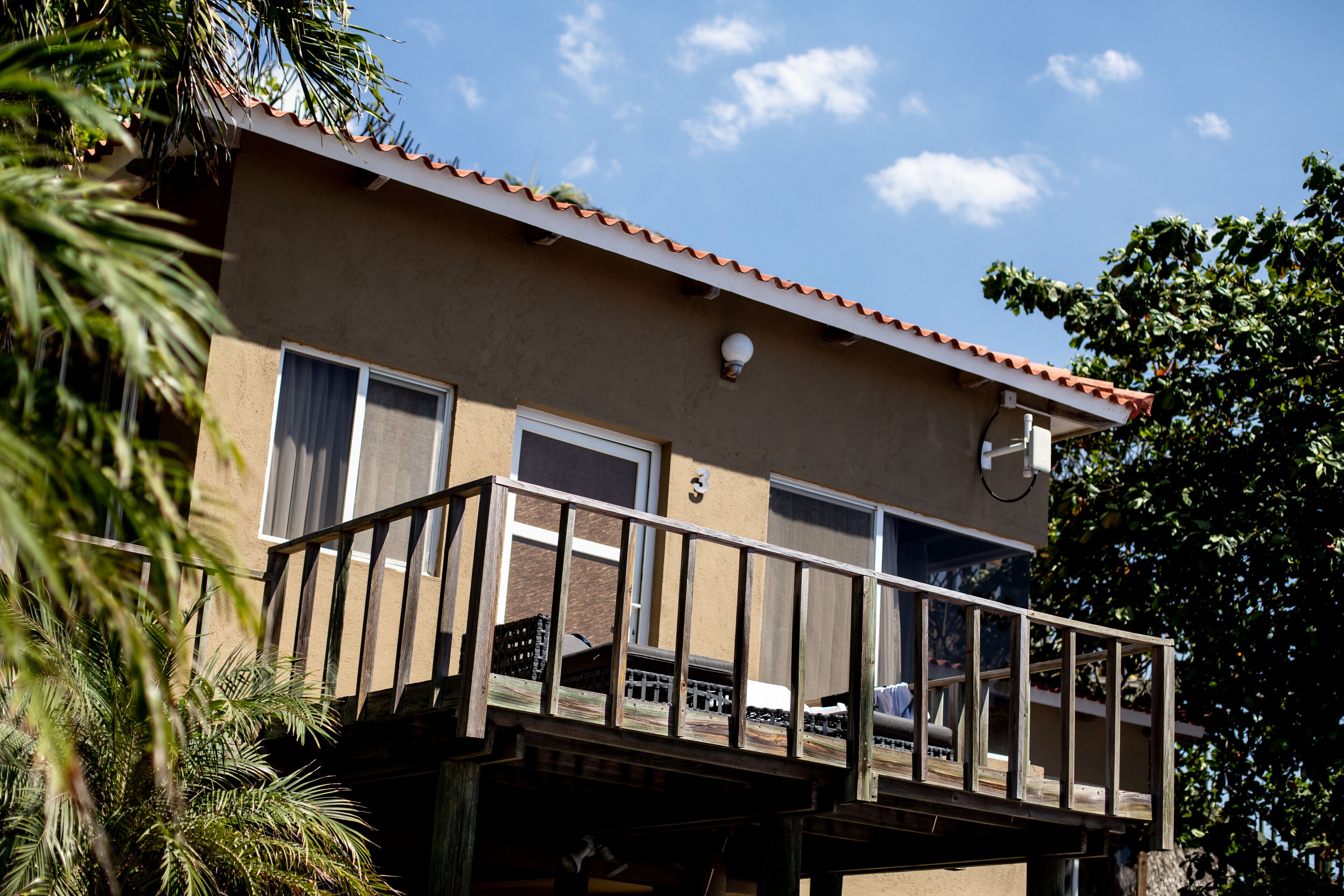 A two-story building with a balcony, a satellite dish, and a door.
