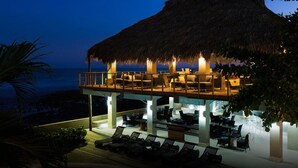 A beachfront resort with a thatched-roof lounge area overlooking the sea, outdoor seating, and a pool area. - Casa de Mar Hotel And Villas (Tamanique)