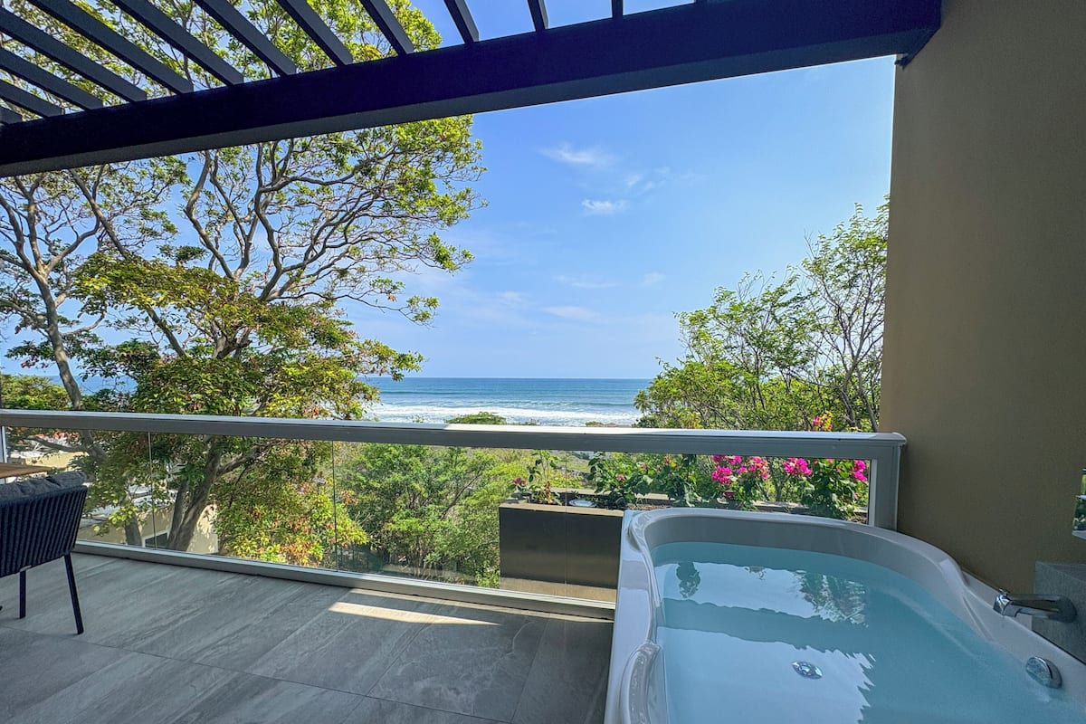 Un balcon avec vue sur l’océan, un jacuzzi et un espace repas.