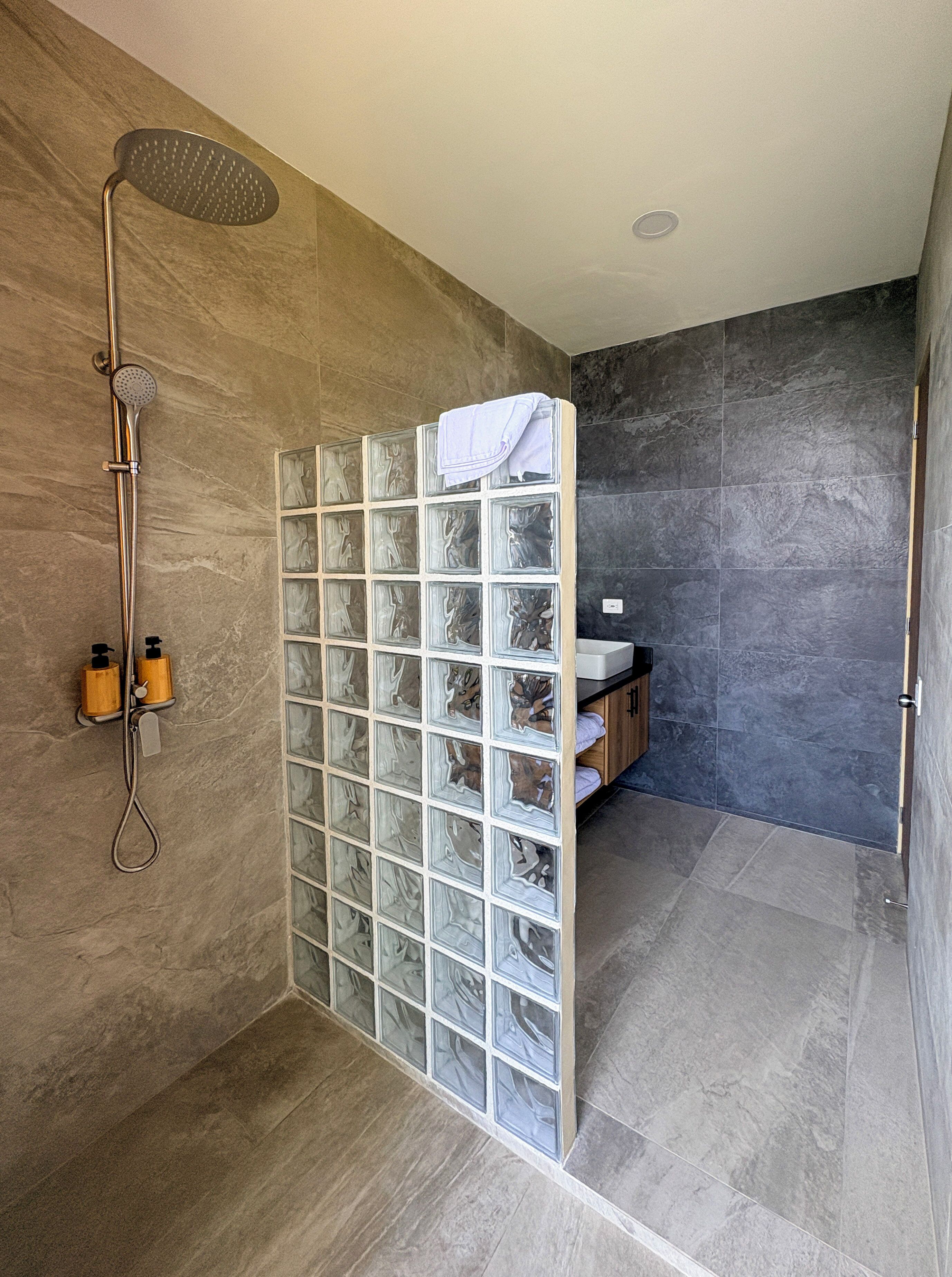 Ein modernes Badezimmer mit einer Duschkabine aus Glas, einer Handbrause und einem integrierten Waschbecken mit Holzschrank.