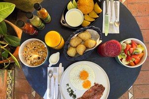 A breakfast table with various food items, including eggs, bacon, croissants, and a fruit bowl.