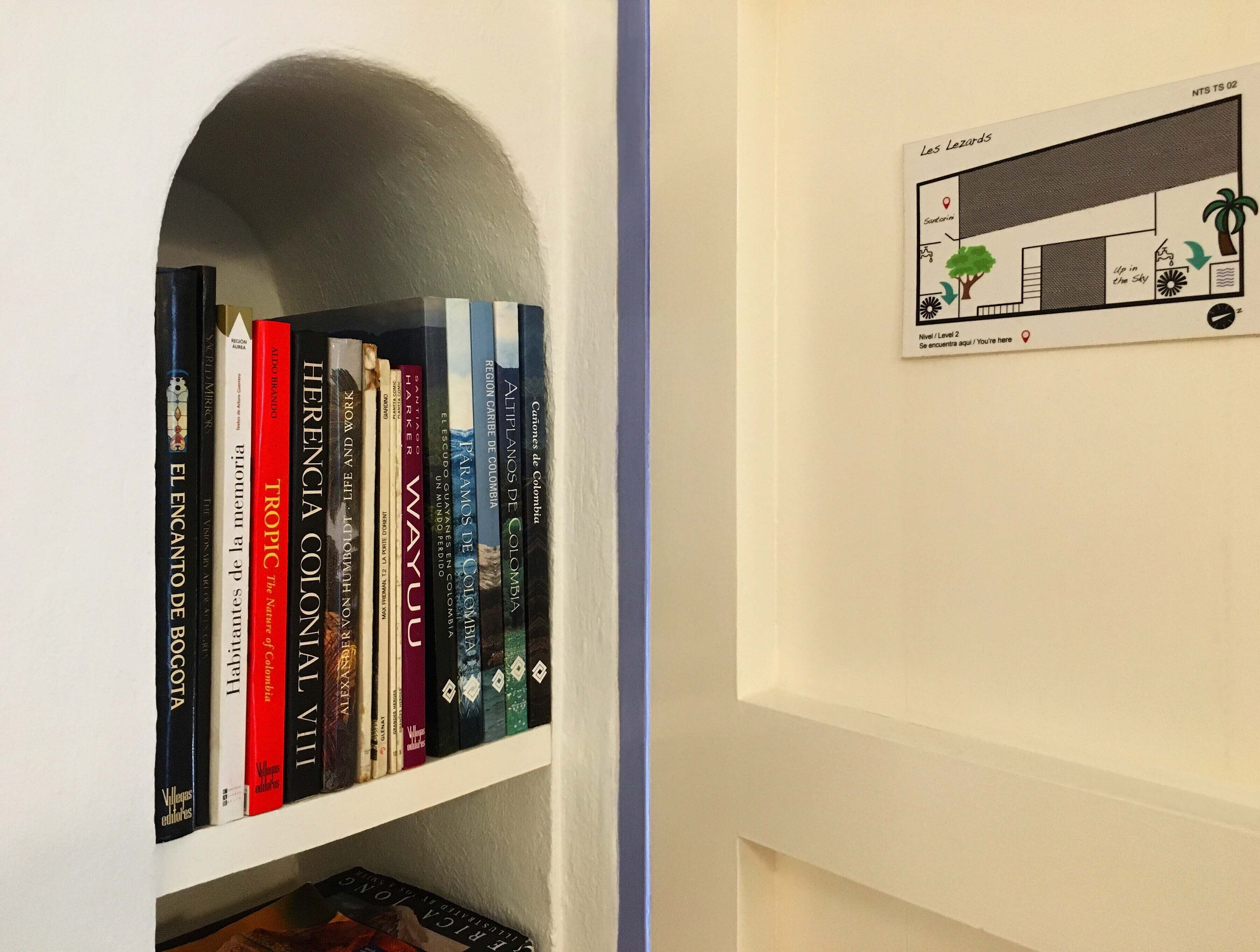 A bookshelf with books and a small architectural drawing on the wall.