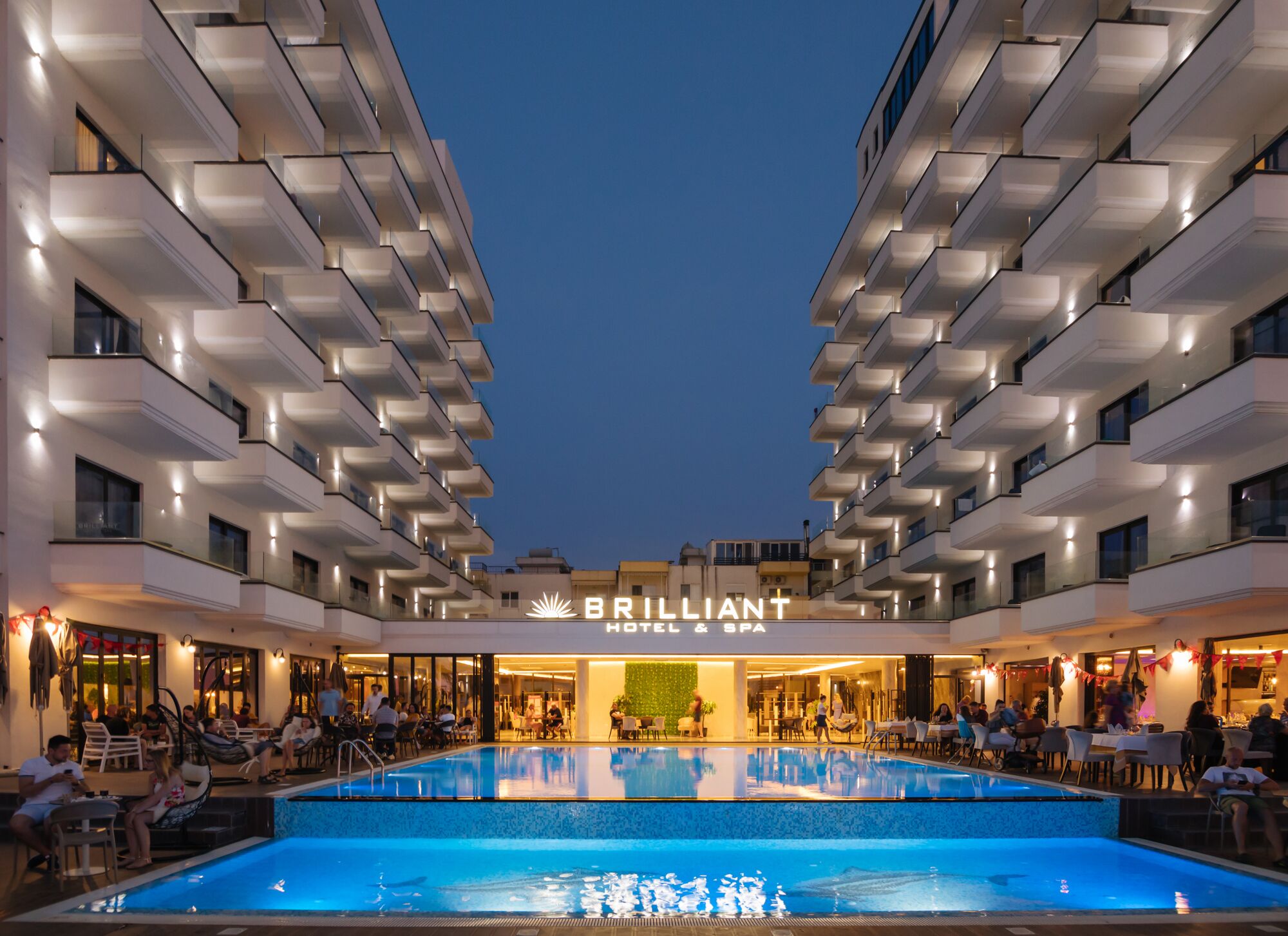 Un hôtel doté d’une grande piscine extérieure, de nombreux balcons et d’une enseigne indiquant « BRILLIANT HOTEL & SPA ».