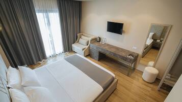 A hotel room with a large bed, a desk, a chair, a TV, and a mirror.