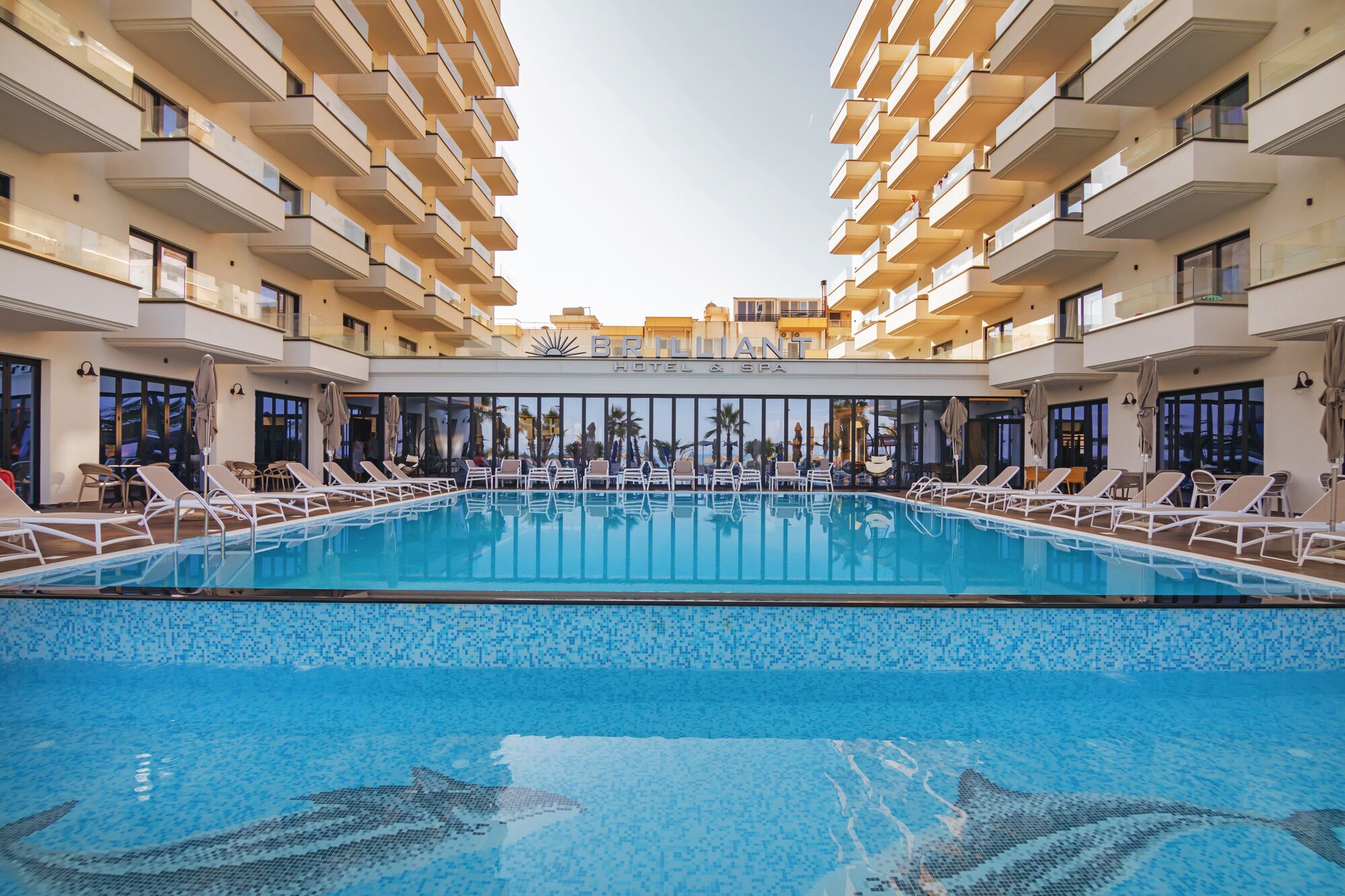 Un hotel amb una gran piscina interior, diversos balcons iairebeds per relaxar-se.