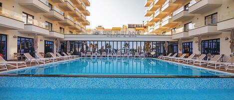 Un hotel amb una gran piscina interior, diversos balcons iairebeds per relaxar-se.