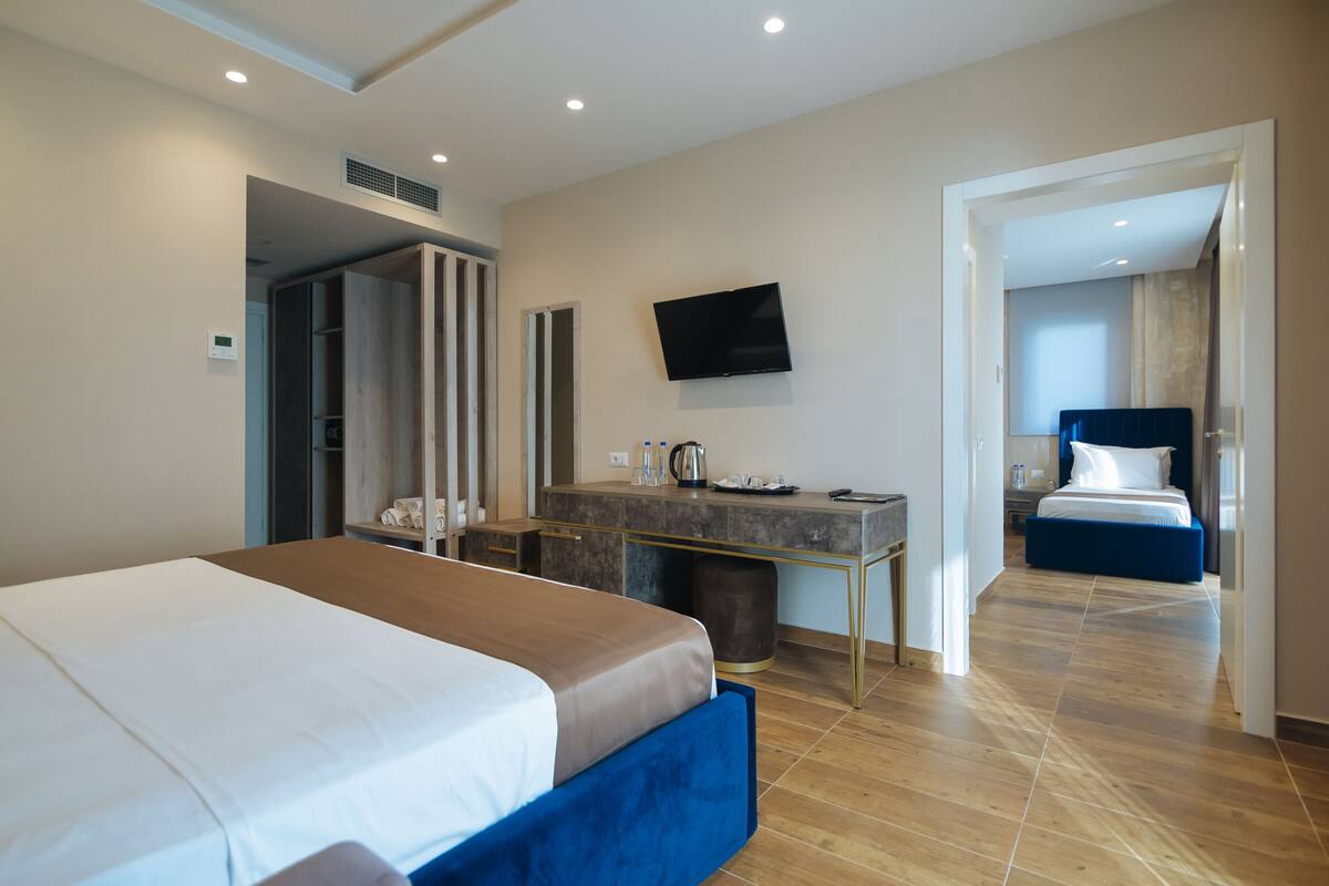 A hotel room with a bed, a desk, a television, and a bathroom visible through an open door.