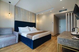 Una habitación de hotel moderna con una cama grande, un sofá, un escritorio y una televisión.