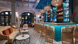 Un espace bar avec des chaises en osier, un comptoir et un sol carrelé.