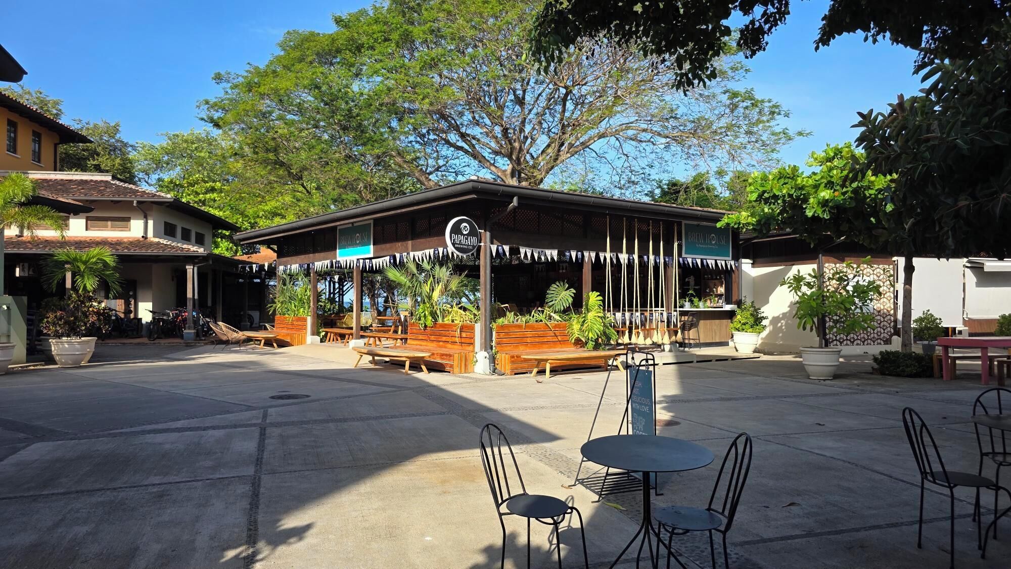 Ein Café mit Außenbereich, ein Schild mit der Aufschrift 'Papagayo' und ein Schild mit 'Green House'.