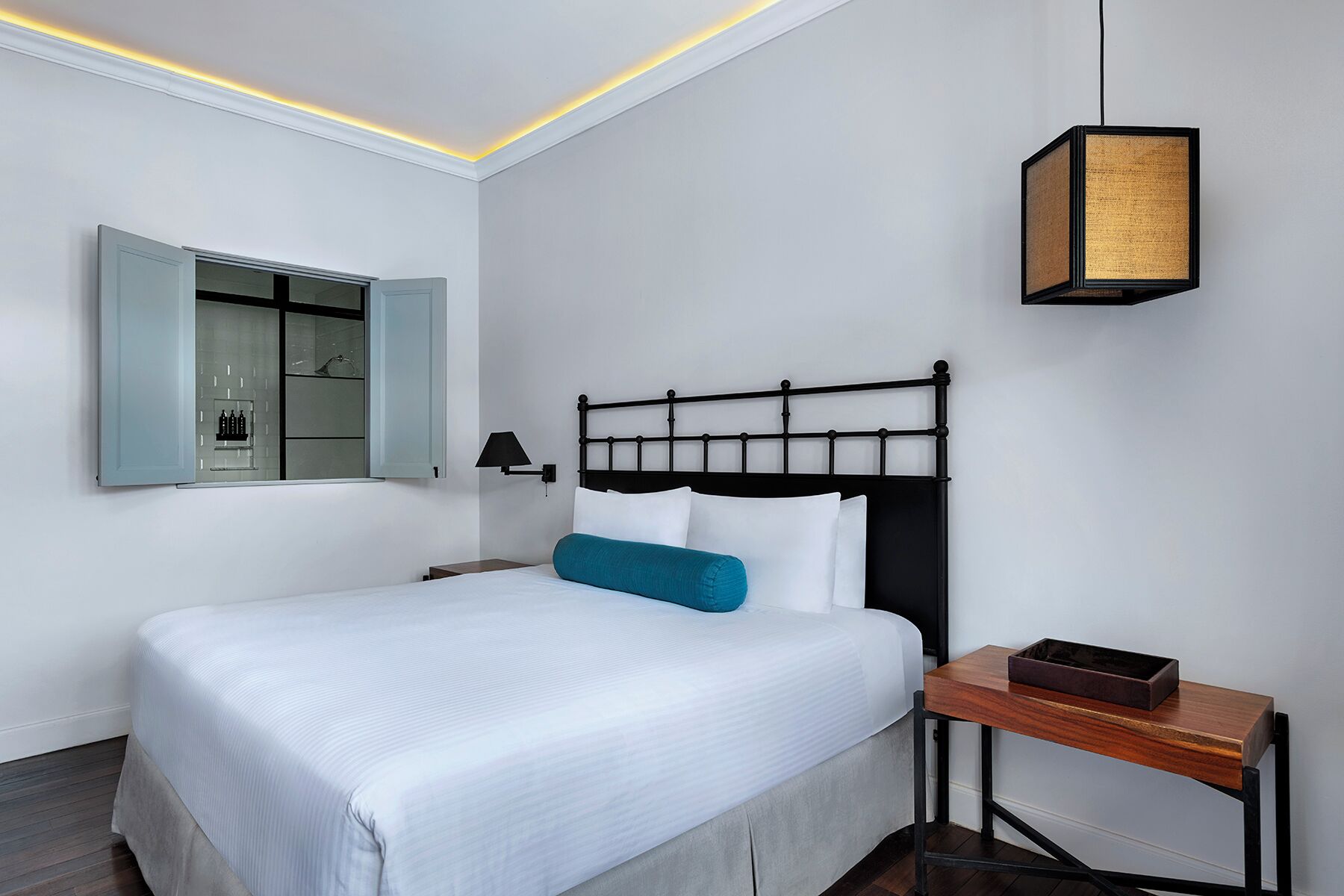 A neatly arranged hotel room with a bed, bedside table, lamp, and a mirror.