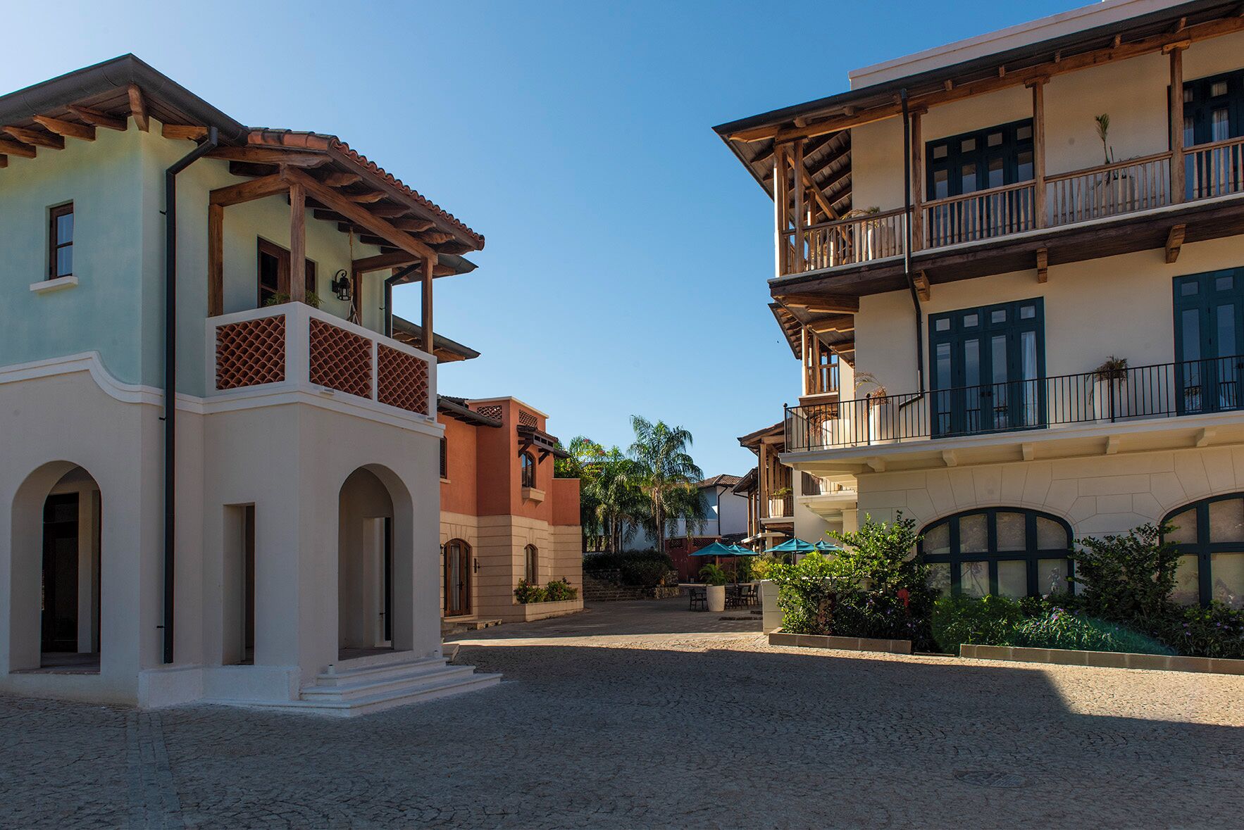 Un patio con suelo de adoquines, un edificio con balcón y otro edificio con fachada de madera.