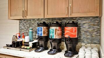A coffee station with three dispensers labeled Regular, Decaf, and Hot, and a tray with coffee cups and condiments.