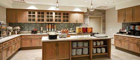 Una cocina moderna con armarios de madera, una isla central y estanterías empotradas.