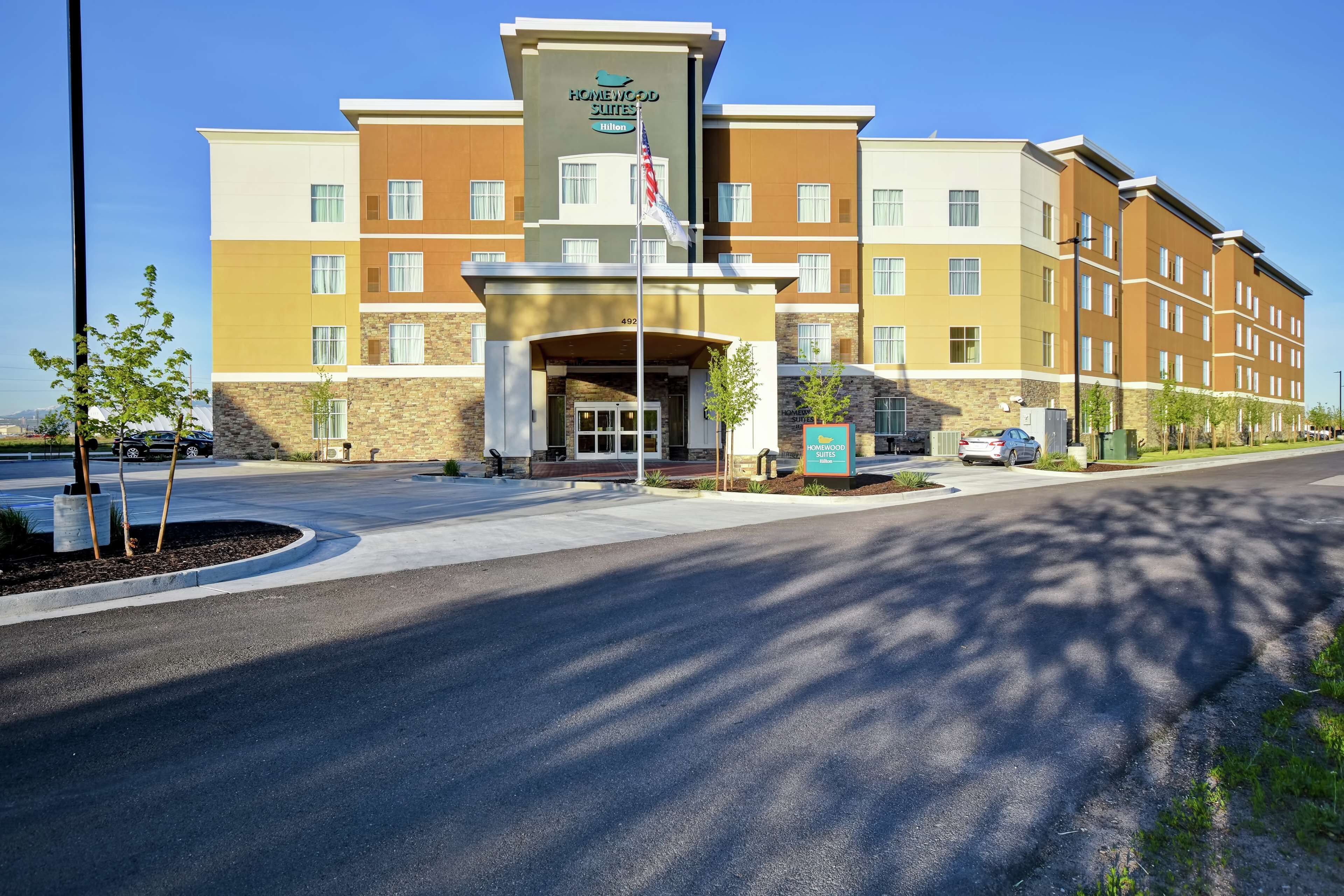 A multi-story hotel with a central entrance, a flag, and a signboard.