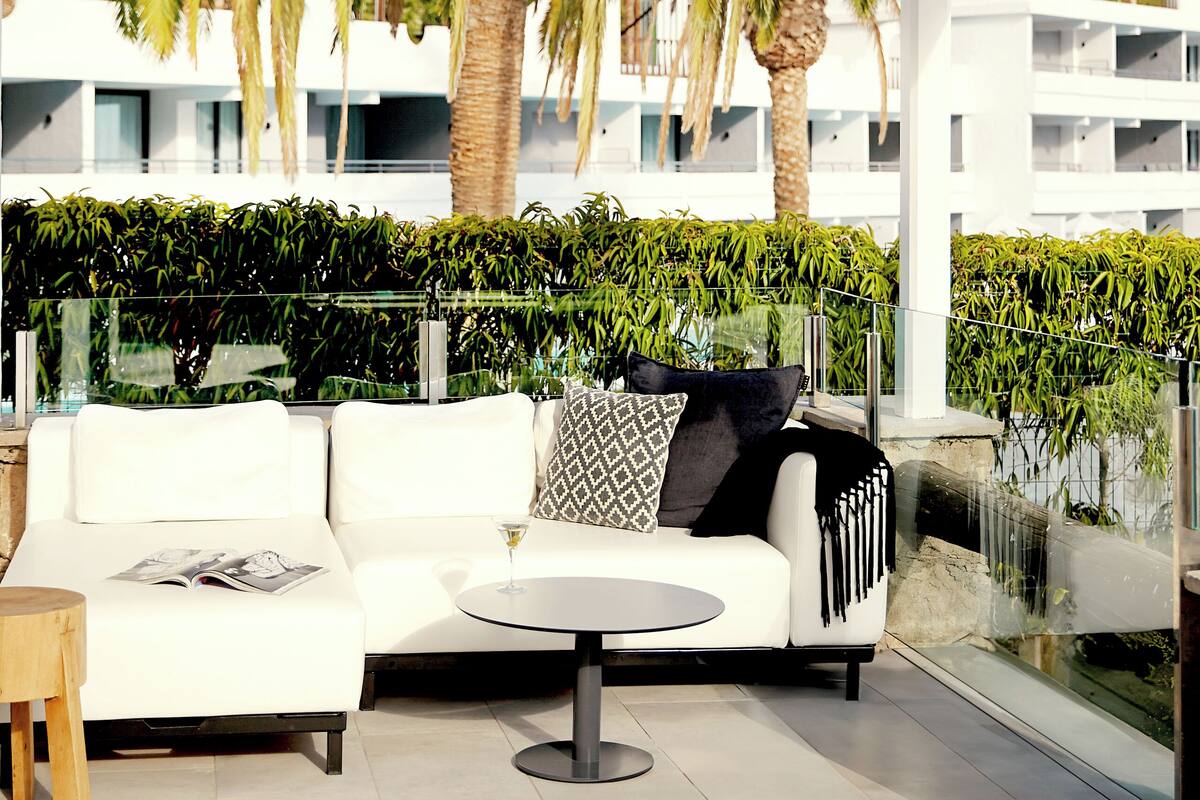 A modern outdoor seating area with a white sofa, a round table, and a magazine.